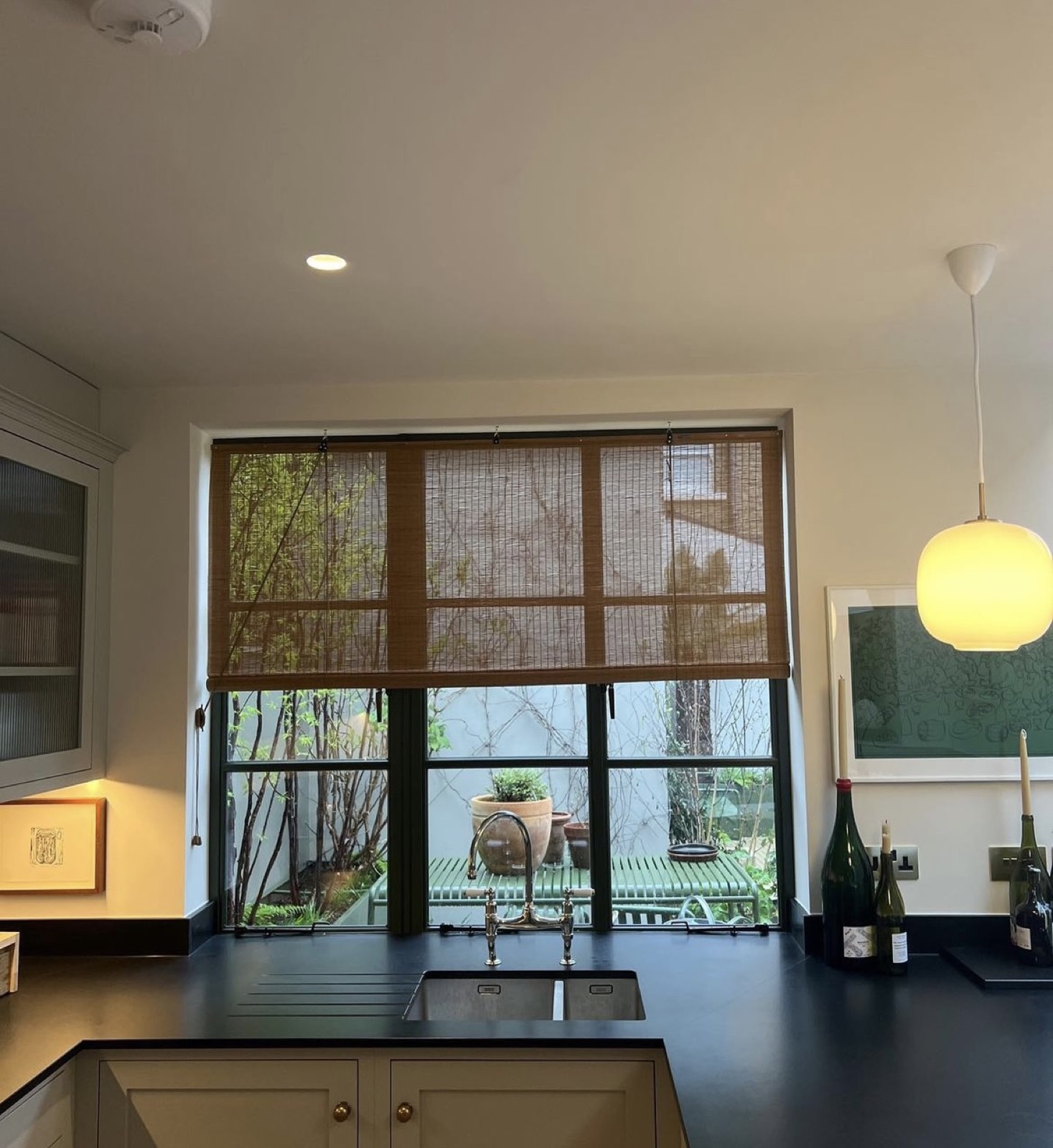 Natural woven roman shade over a kitchen window